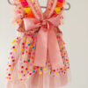 back view of a bright colour confetti spotted children's birthday party dress. This dress is handmade in New Zealand. A large pink bow ties the back of the dress.