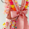 close up, back view of a bright colour confetti spotted children's birthday party dress. This dress is handmade in New Zealand. A large pink bow ties the back of the dress.