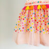 a close up a bright colour confetti spotted children's birthday party dress. This dress is handmade in New Zealand
