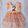 Child's birthday party dress with bright colour confetti spots and number 2 on the front.