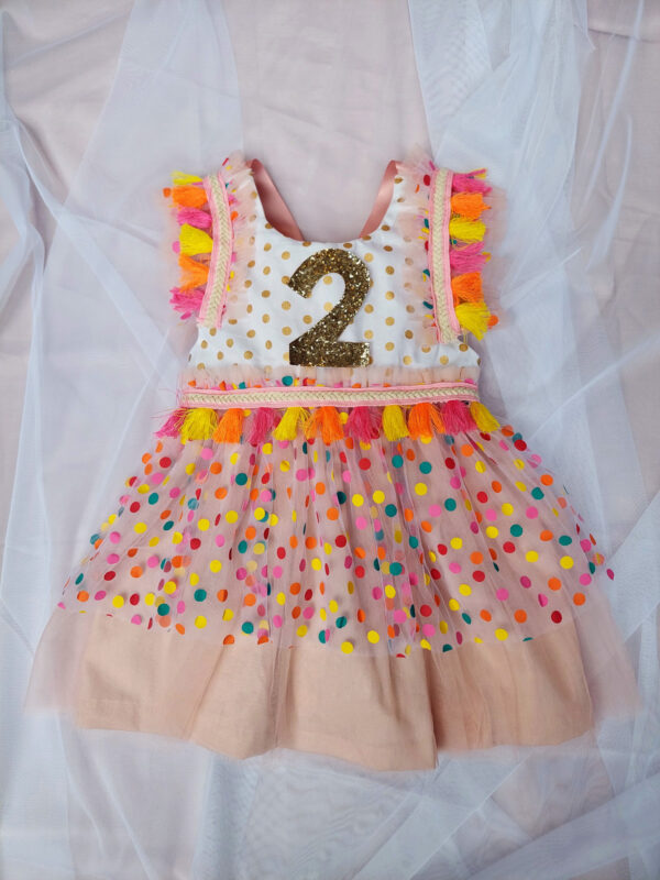 Child's birthday party dress with bright colour confetti spots and number 2 on the front.