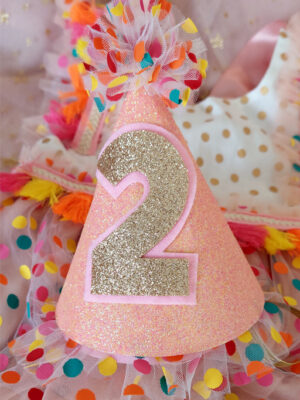 Front view of a sparkling pink 'confetti' birthday party hat, with custom golden glitter number 2 displayed on the front.