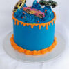 Racing car birthday cake with blue frosting, orange drip, and toy cars