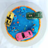 Racing car birthday cake with blue frosting, orange drip, and toy cars